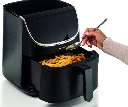 Black air fryer with french fries being served using a spoon.