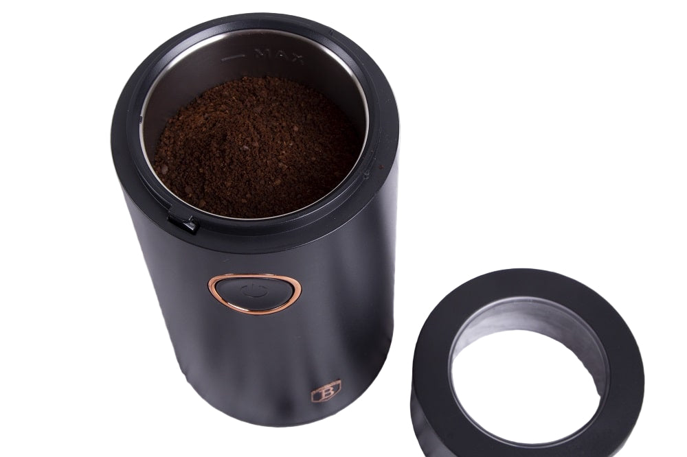 Black coffee grinder with coffee beans on a wooden surface