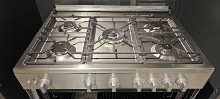 Stainless steel gas stove with multiple burners and control knobs on a black background