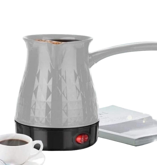 Gray electric kettle with geometric pattern on a white surface next to a cup of coffee.