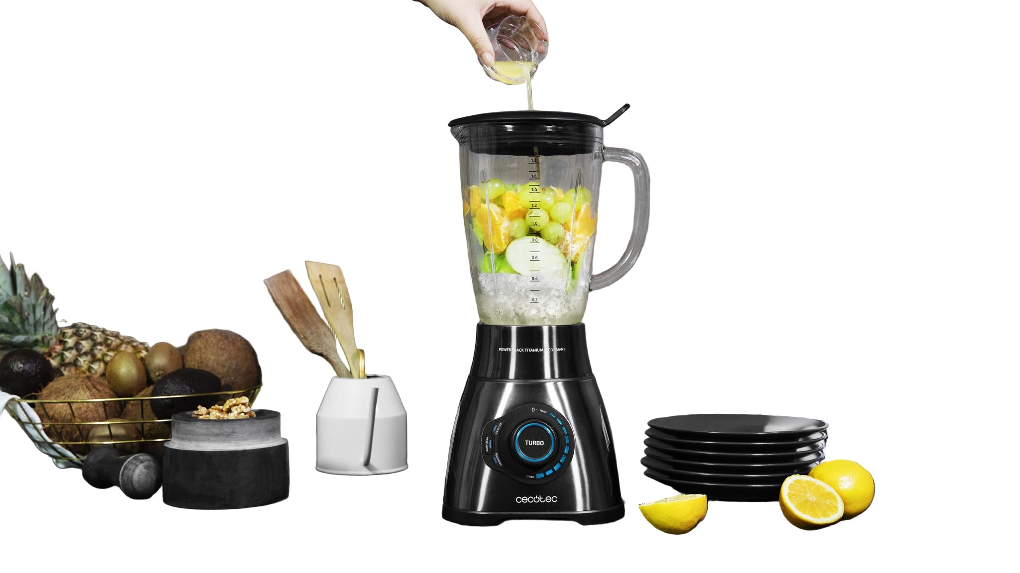 Blender with fruits and a person pouring liquid into it on a kitchen counter.