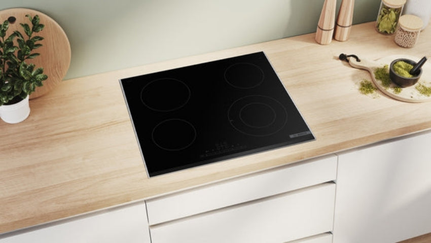 Black induction cooktop on a wooden kitchen counter with white cabinets.