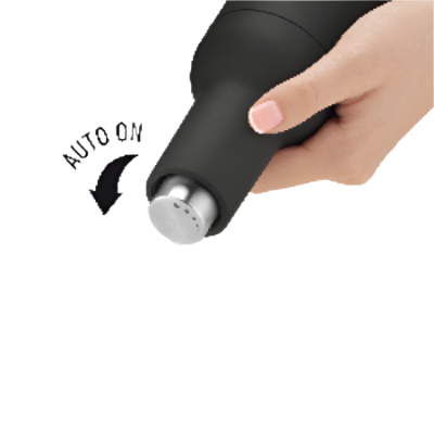 Black pepper grinder being used with auto-on feature, showing pepper falling onto a white surface.