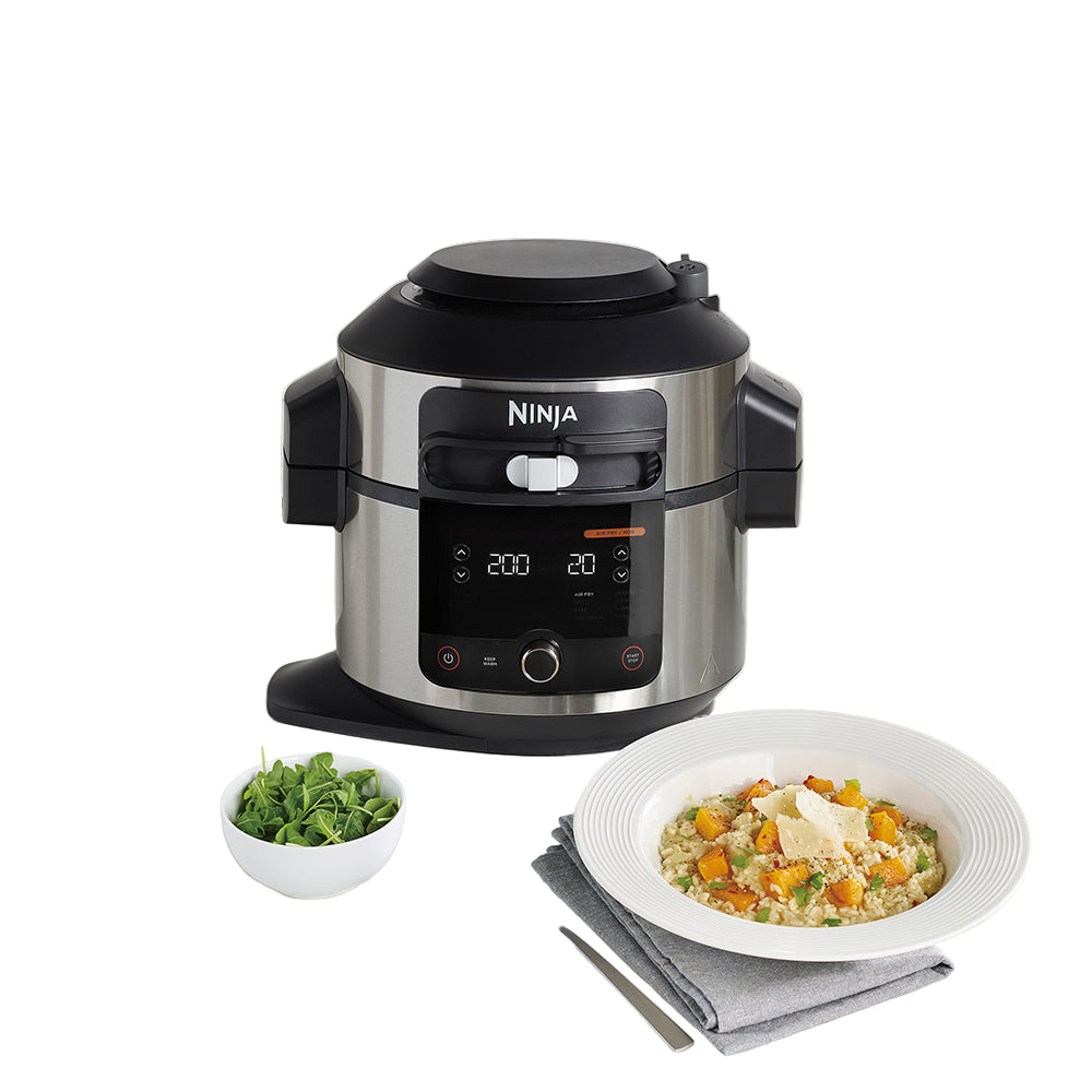 Ninja appliance on a kitchen counter with a plate of food and salad.