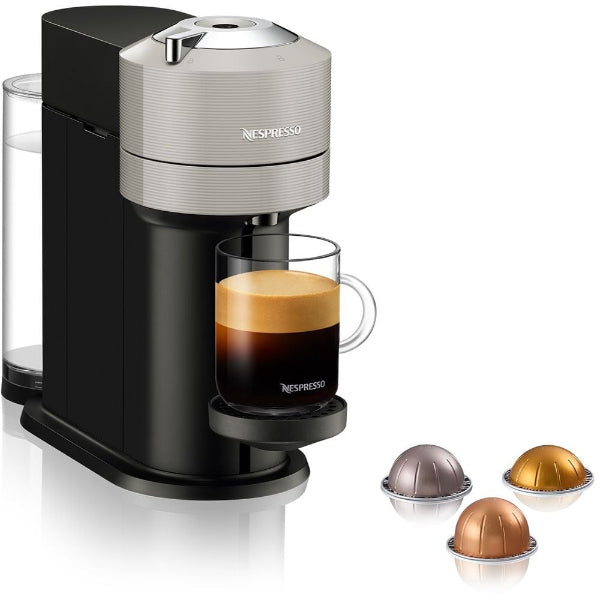 Nespresso coffee machine with a glass of espresso and three capsules on a white background