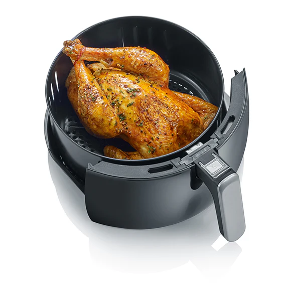 Air fryer with a roasted chicken inside on a white background